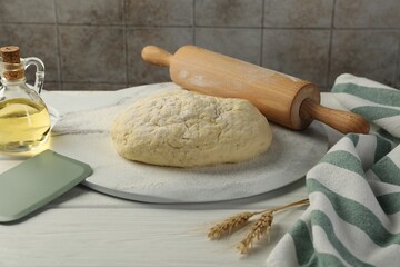 Fresh dough, rolling pin, oil and spikes on white wooden table