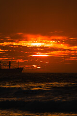 atardecer del sol en el mar con barco industrial y nubes