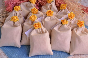 Wedding favors cotton gift bags yellow flowers decoration, blue color jute background, party event...