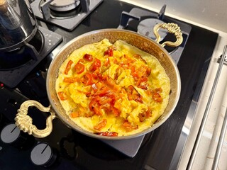 Scrambled eggs with red bell pepper in copper bowl