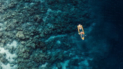 Woman kayaking in clear blue ocean on transparent kayak. Above drone view with copy space