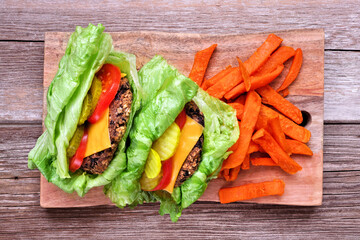 Healthy vegetarian plant based cheese burgers with a no carb lettuce bun. Overhead view on a rustic wood background. Plant-based diet concept.