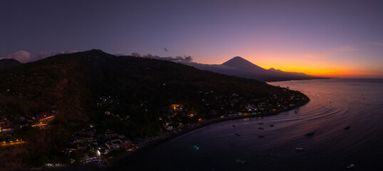 Panoramic drone view of coastline with volcano mount and sunset twilight with quiet sea in Bali.