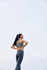 Athletic woman in gray activewear enjoying workout outdoors, demonstrating strong posture and...