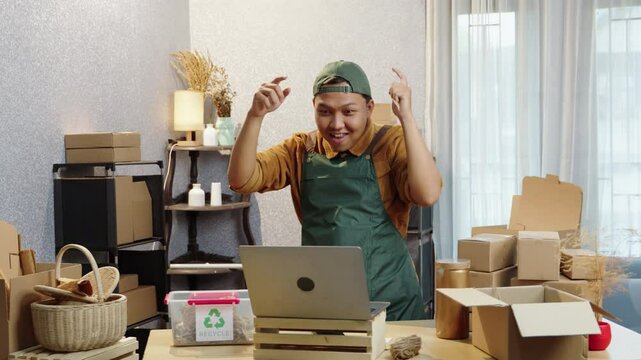 Owner of a small business celebrating successful sales at home. Dancing joyfully while preparing packages for delivery. Small business, home office, happy owner, SME, order fulfillment