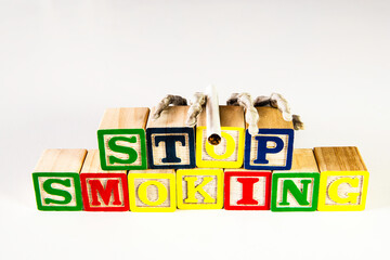 skeleton hand holding cigarette on wood blocks spelling stop smoking with white background