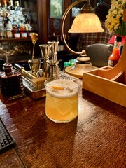 Whiskey sour cocktail at pub bar with orange peel
