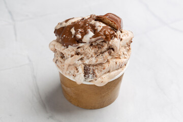 Chocolate ice cream dripping with cookie crumbles and syrup, cascading over paper cup's rim in decadent dessert display