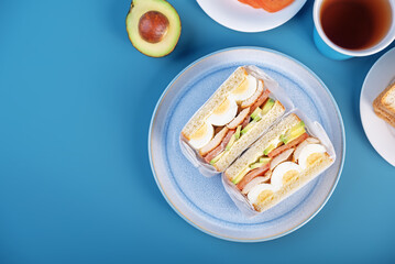 Eggs fired meat avocado tomato sandwiches in a plate