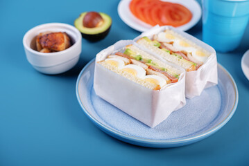 Eggs fired meat avocado tomato sandwiches in a plate