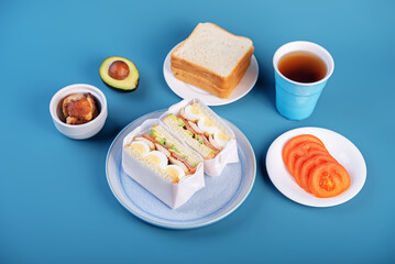 Eggs fired meat avocado tomato sandwiches in a plate