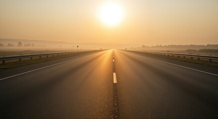 Peaceful sunrise over a long empty highway surrounded by misty fields