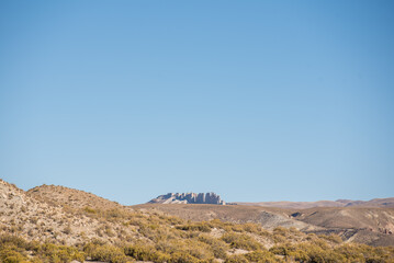 Beautiful Andean landscape with clouds and a blue sky illuminated with natural light in the heights	, with a view of the Cerro las velas a dented rocky formation in atocha bolivia 
