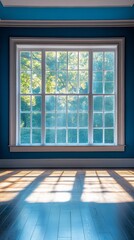 Fototapeta premium Bright sunlight illuminates empty room with blue walls and window on a clear day