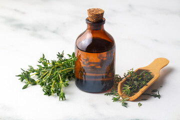 Bottle of thyme essential oil with fresh thyme