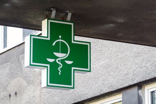 Asclepius staff symbol on green cross of pharmacy