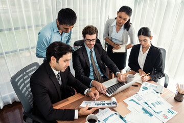 Diverse group of business analyst team analyzing financial data report paper on office table. Chart and graph dashboard by business intelligence analysis for strategic marketing planning Meticulous