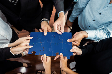 Top view multiethnic business people holding jigsaw pieces and merge them together as effective...