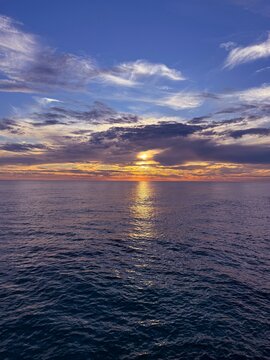 Dusk sky clouds over glittering ocean at evening.
