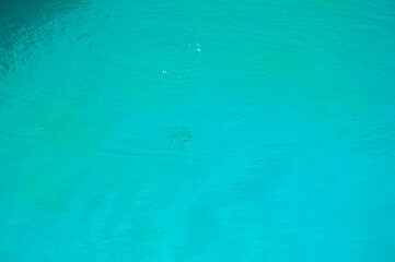 Turquoise background of clear turquoise sea water. Idyllic summer vacation. Caribbean sea. Rippled surface. Sea water surface. Ripple water of ocean. Aquamarine ocean nature. Crystal-clear water