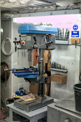 Workshop drill press with various tools in a well-organized garage during daylight