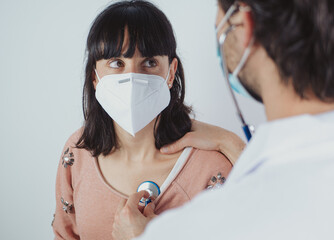Patient consultation in a medical setting with health professional wearing masks and using a...