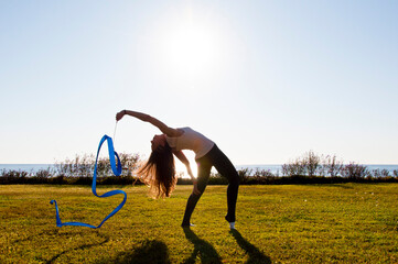 Woman silhouette with gymnastics ribbon. Rhythmic gymnast performing yoga. Practice exercise....