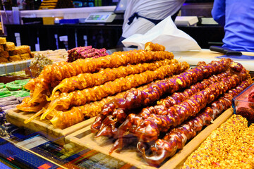 Bunches of bright traditional churchkhela sweets made of different nuts. Colorful churchkhelas at georgian market.