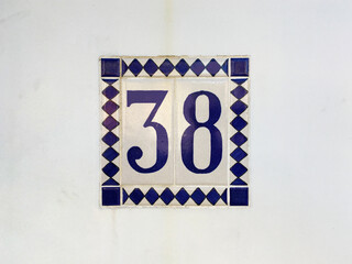 Fototapeta premium Tiled house number 38 on a building wall