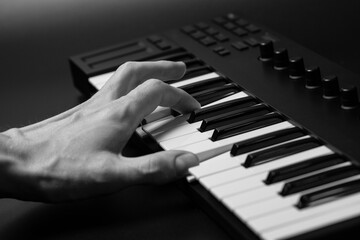 Fototapeta premium A midi keyboard with a man's hand playing it, piano keys.