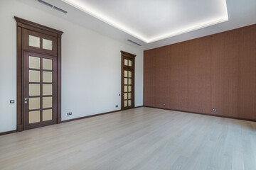 A spacious room with a final finish. The doors are made of brown wood with glass windows. Light laminate, one wall is decorated with brown wallpaper. Unfurnished.