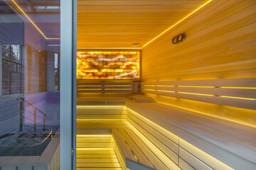 Traditional sauna made of light wood. Soft lighting, beautiful decor. The pool is behind a glass...