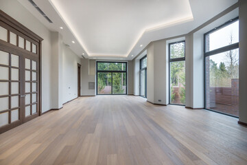 A bright hall in a luxurious mansion. Dark doors with frosted glass windows, panoramic windows with a view of the courtyard. Unfurnished.