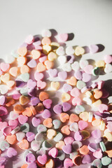 Heart-shaped pastel candies with sweet messages scattered under soft sunlight