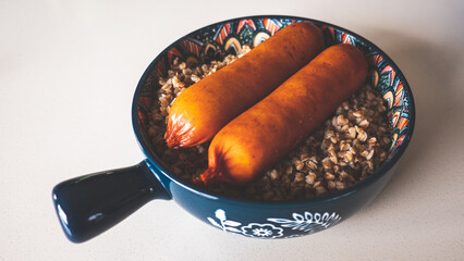 Buckwheat kasha and two sausages in a nice cure ceramic plate bowl