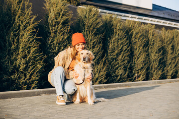 Smiling woman hugging golden retriever dog outdoors in the street