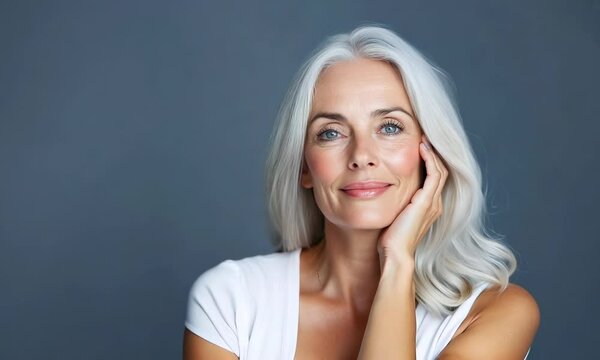 Beautiful senior woman with gray hair posing on gray background