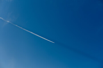 Contrails create delicate patterns across the bright blue sky during a sunny day
