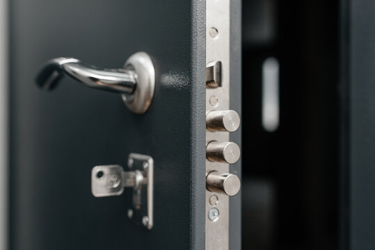 modern metal door to apartment, lock in three rods form, door slightly open, key in keyhole, coming home concept - Powered by Adobe