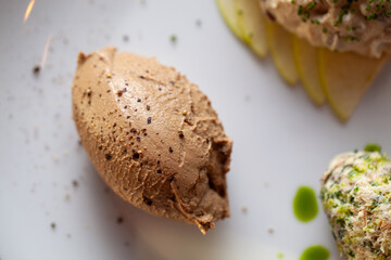 Creamy chicken liver pate garnished with black pepper on a white plate with green apple slices
