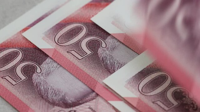 UK money. british pounds slowly counted in fingers. GBP Currency. New 50 pound notes