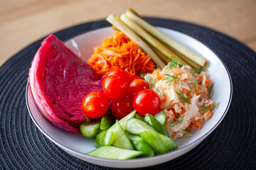 A colorful assortment of Russian pickled vegetables including cabbage, carrots, tomatoes, cucumbers, and pickles on a plate