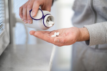 Close up of man's hands pouring tablets out of bottle