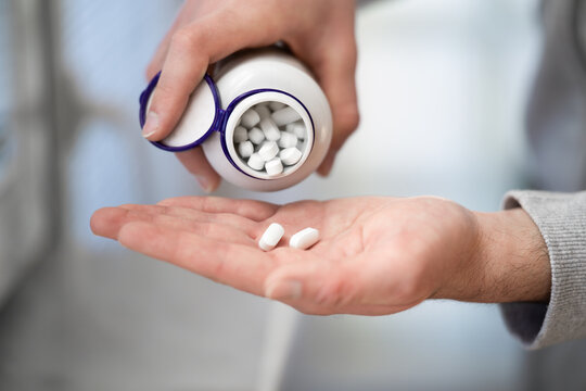 Close up of man's hands pouring tablets out of bottle