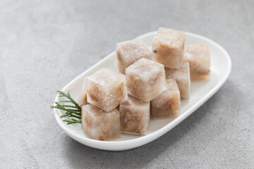 Aspic. Jellied meat in the shape of a mini cubes. On a plate. Light gray background. Close up