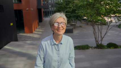 Smiling adult Caucasian businesswoman mature senior middle-aged gray-haired business woman happy...