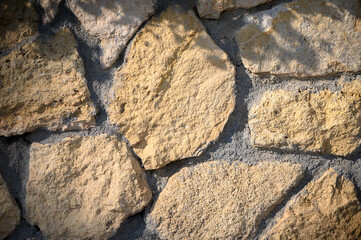 Rustic stone wall showcasing intricate textures and natural patterns under sunlight in a tranquil setting