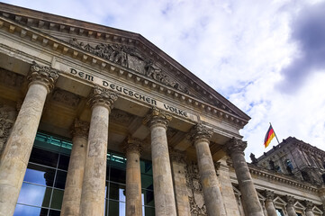 Reichstag building facade with german flag waving in Berlin, Germany