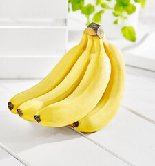 Kiść bananów na białym stole w jasnym świetle © Jolaya