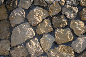Natural stone wall showcasing rustic textures and earth tones in a sunlit outdoor setting